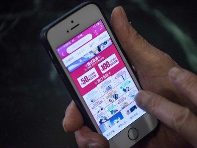 A man looks at a Chinese online store's website on his smartphone in Beijing on November 11, 2017. China's smartphone masses splurged billions of dollars in an e-commerce bonanza on November 11 as consumers rushed to snap up bargains on "Double 11", billed as the world's biggest one-day online shopping festival. 
PHOTO: AFP