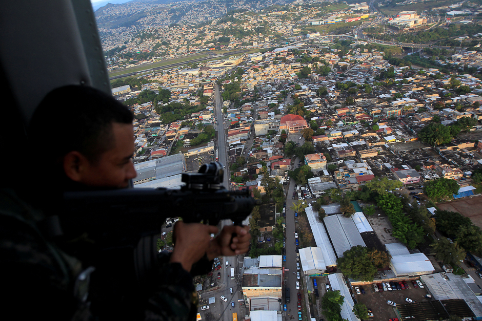 A soldier in a military helicopter aims his weapon during a patrol of the operation 'Peace and Democracy II' as part of the security measures for the November 26 presidential elections, in Tegucigalpa. PHOTO: REUTERS