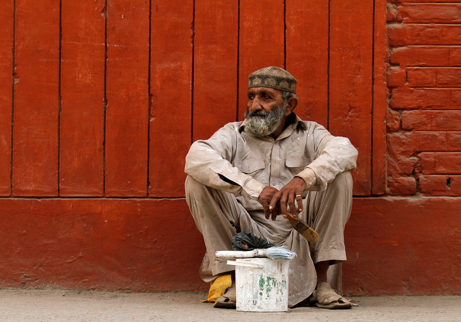 An unemployed painter sits on the side of the street waiting to be hired for a temporary job in Peshawar, Pakistan. PHOTO: REUTERS