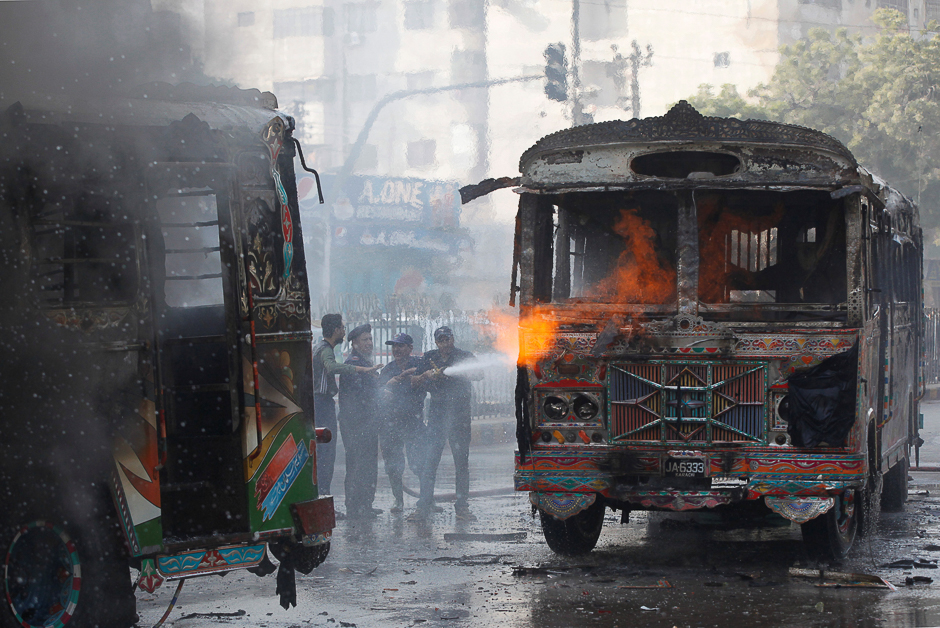 Firefighters douse a fire on buses, which according to local media were set ablaze by people after a girl was killed due to over speeding, along a road in Karachi. PHOTO: REUTERS