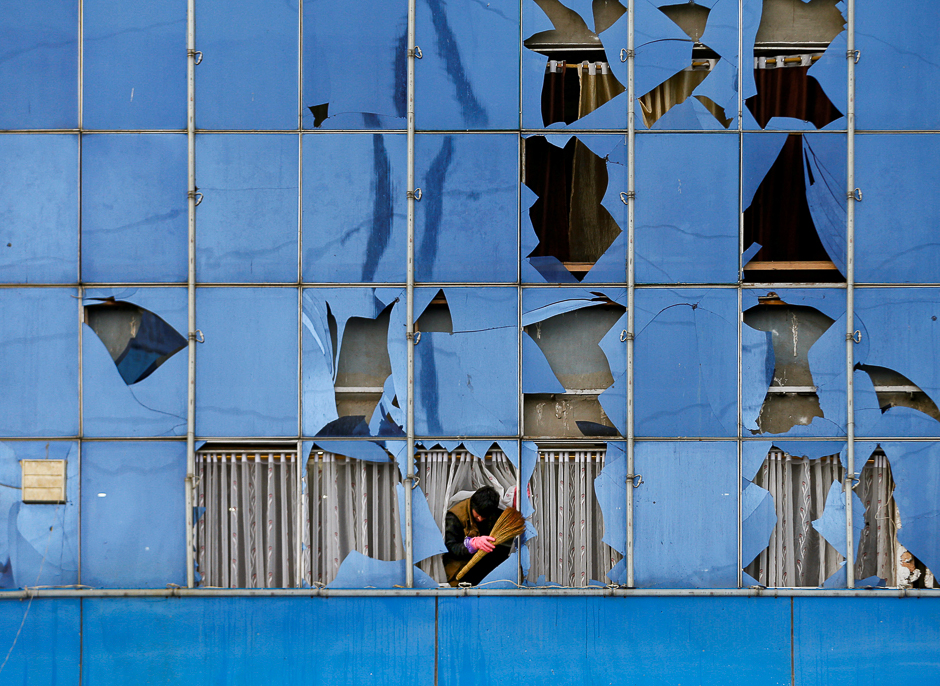 A man removes broken glass from a building after a suicide bomb attack in Kabul, Afghanistan. PHOTO: REUTERS
