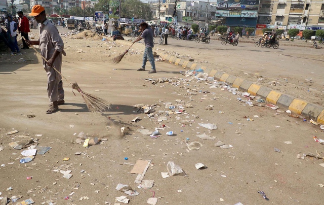 Protesters clean the area around Numaish Chowrangi in Karachi after the sit-in was called off. PHOTO: ONLINE