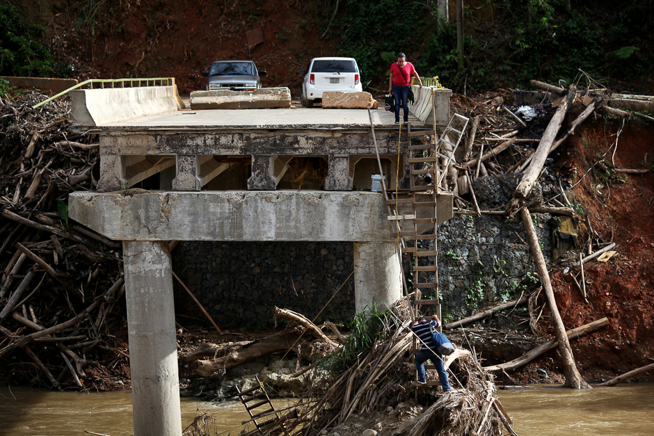 A woman looks as her husband climbs down a ladder at a partially destroyed bridge, after Hurricane Maria hit the area in September, in Utuado, Puerto Rico. PHOTO: REUTERS