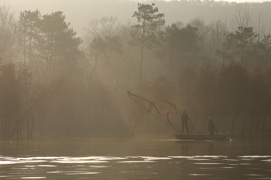 Fishermen cast their fishing net into a lake on a foggy day in Huai'an, Jiangsu province, China. PHOTO: REUTERS