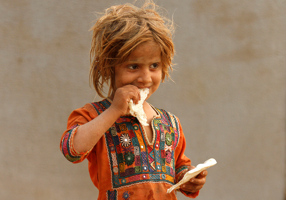 A boy holds for camera a naan, a traditional bread, after it was cooked in an oven at a shop in Karachi, Pakistan. PHOTO: REUTERS