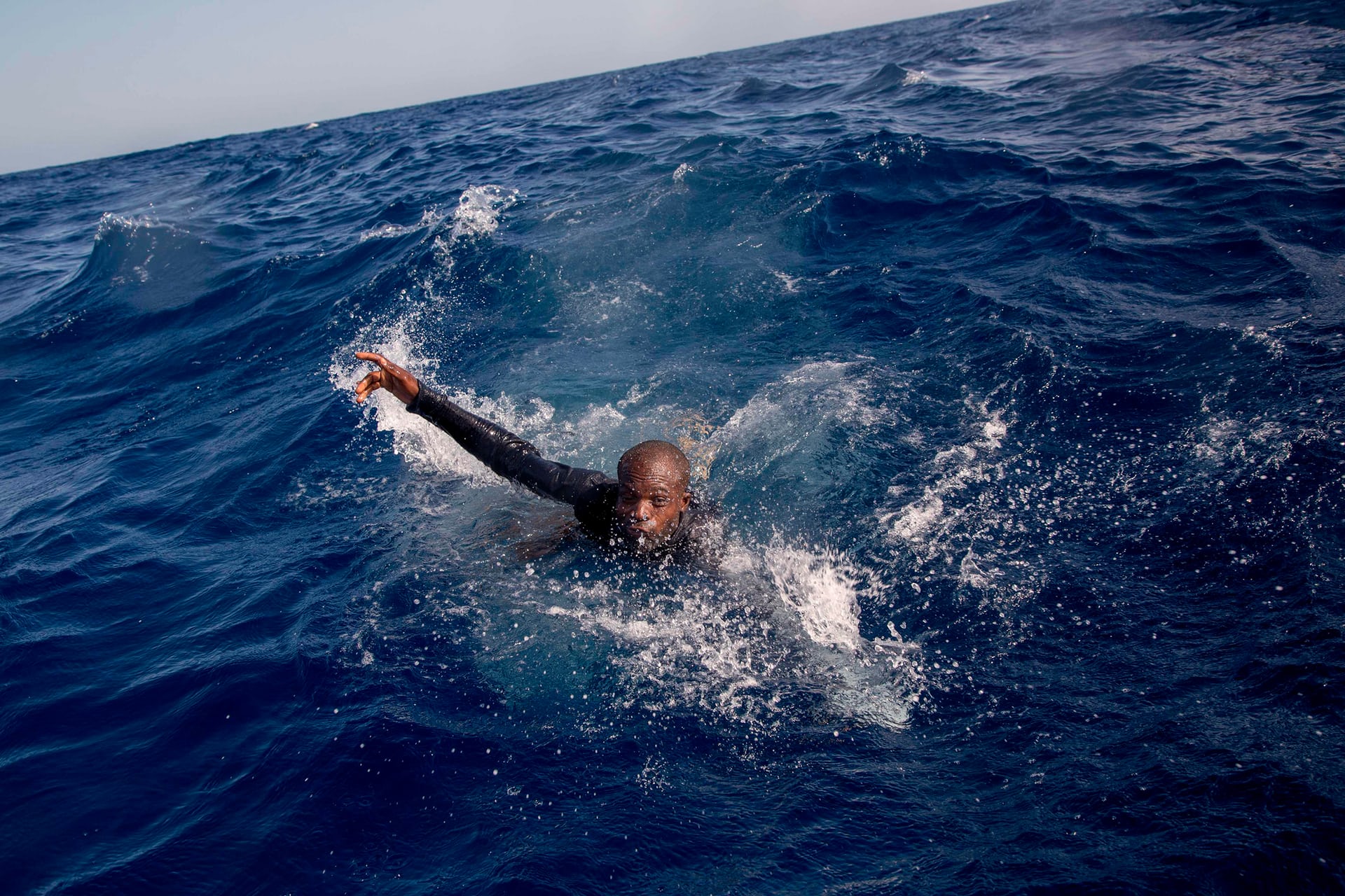 A migrant tries to board a boat belonging to the German non-governmental organisation Sea-Watch. A shipwreck resulted in the death of five people, including a newborn child, Mediterranean Sea. PHOTO: AFP