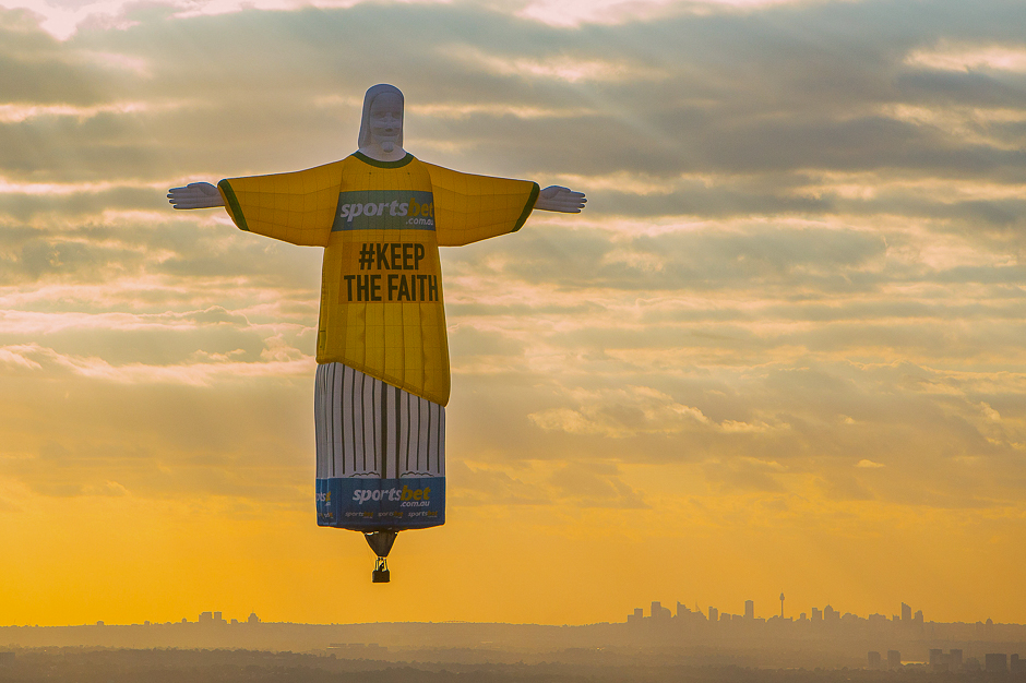 A balloon shaped in the famous 'Christ the Redeemer' statue that overlooks the Brazilian city of Rio de Janeiro floats at sunrise as part of an advertisement campaign for an online betting company above the Australian city of Sydney. PHOTO: REUTERS