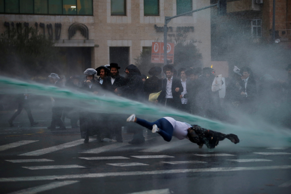 A bystander falls as Israeli police spray water during a demonstration by ultra-Orthodox Jews in Jerusalem. PHOTO: REUTERS