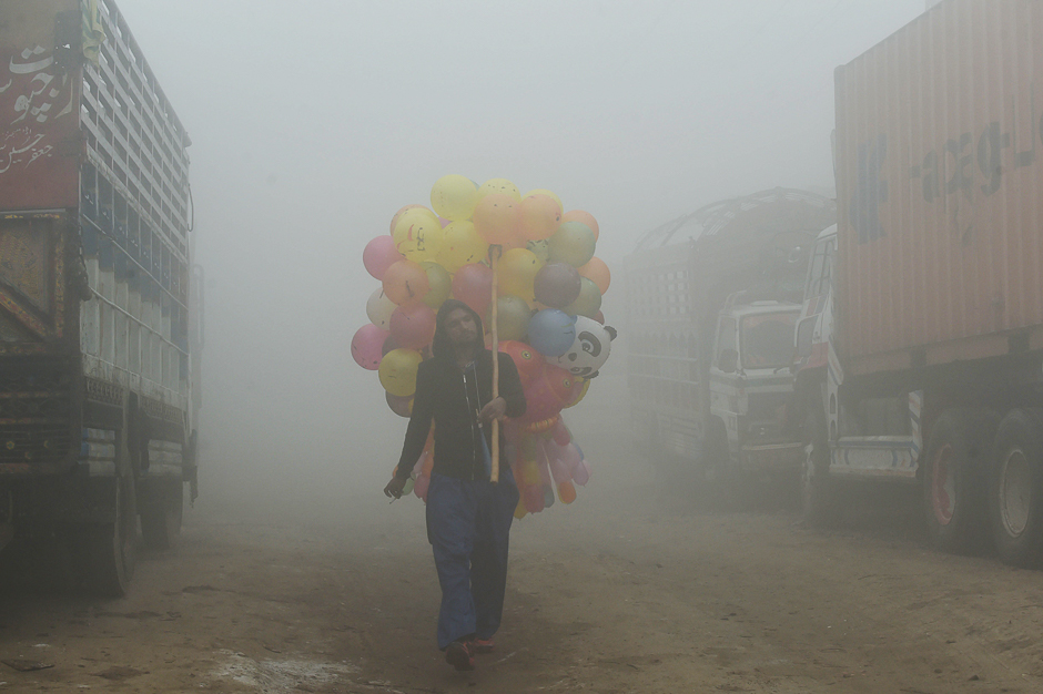 A Pakistani vendor carries baloons on a street amid heavy smog in Lahore. PHOTO: AFP