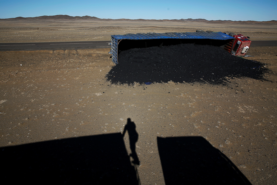 A photographer casts his shadow near a coal truck which flipped over at Khanbogd Soum, near the border with China in the Gobi desert, Mongolia. PHOTO: REUTERS