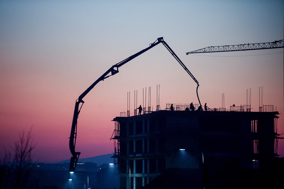 Employees are seen working at a construction site of a new project as the sun sets in Pristina. PHOTO: AFP