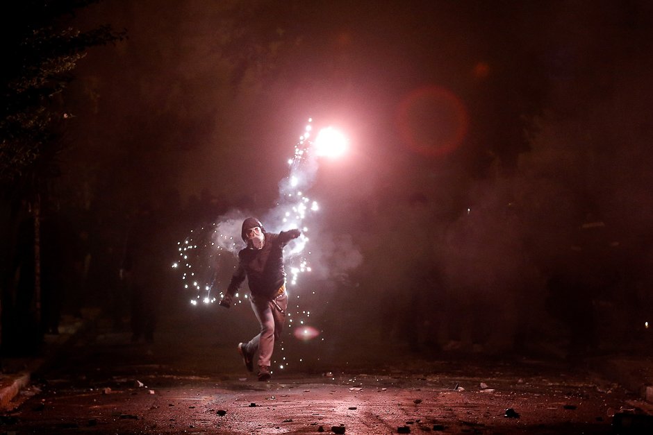 A hooded protester throws a flare during clashes following a rally marking the 44th anniversary of a 1973 student uprising against the military dictatorship that was ruling Greece, in Athens, Greece. PHOTO: REUTERS