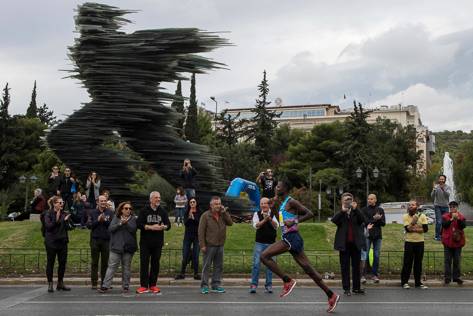 Kenya's athlete Samuel Kalalei (R) runs to victory in front of a statue, made of glass, called 