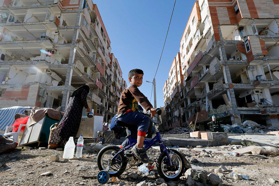 An Iranian boy rides a bicycle through the rubble past damaged buildings in the town of Sarpol-e Zahab in Iran's western Kermanshah province near the border with Iraq. PHOTO: AFP