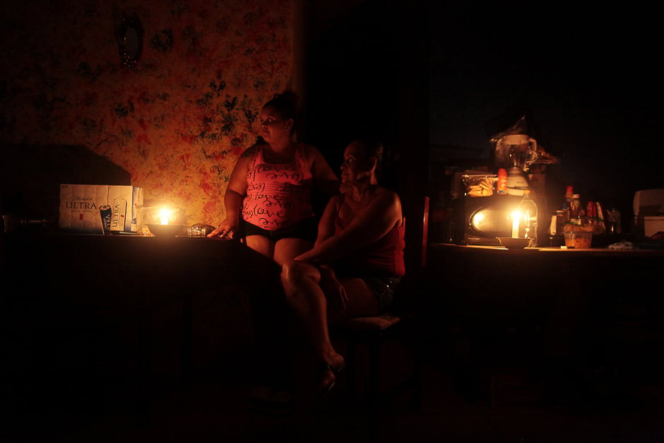 Jaimy Liz Villarini (L) and Magda Rodriguez sit in candle light at their home after Hurricane Maria hit the island and damaged the power grid in September, in Vega Alta, Puerto Rico. PHOTO: REUTERS