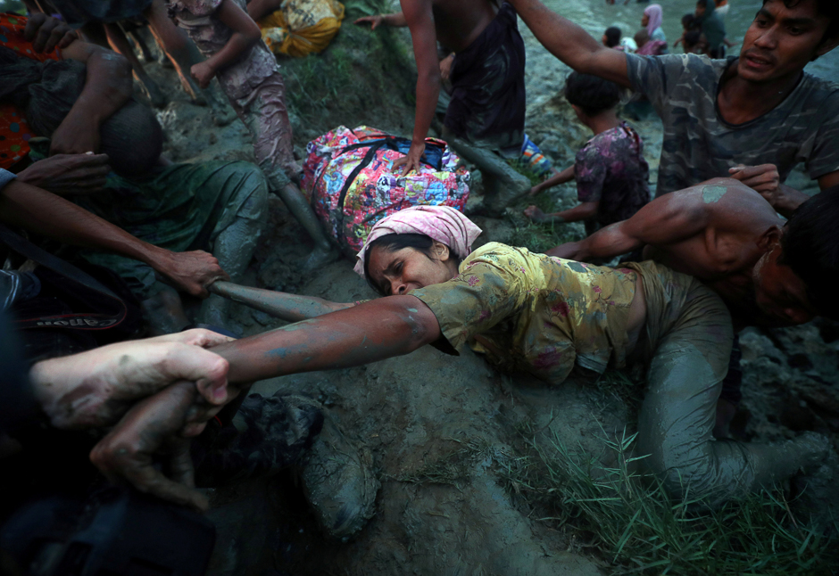 Photographers help a Rohingya refugee to come out of Nad River as they cross the Myanmar-Bangladesh border in Palong Khali, near Cox's Bazar, Bangladesh. PHOTO: REUTERS