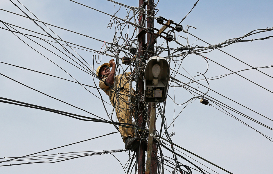 A worker repairs power lines on a pole in Kochi, India. PHOTO: REUTERS