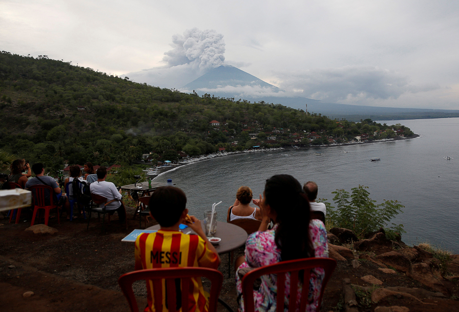 People watch Mount Agung volcano erupt from a cafe near Amed, Karangasem Regency, Bali, Indonesia. PHOTO: REUTERS
