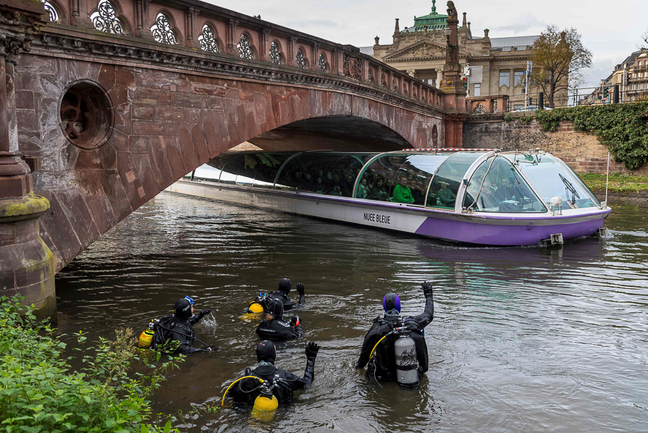 Divers wave at people in a tourist boat, during a cleanup mission of the Ill River in Strasbourg, eastern France. PHOTO: AFP