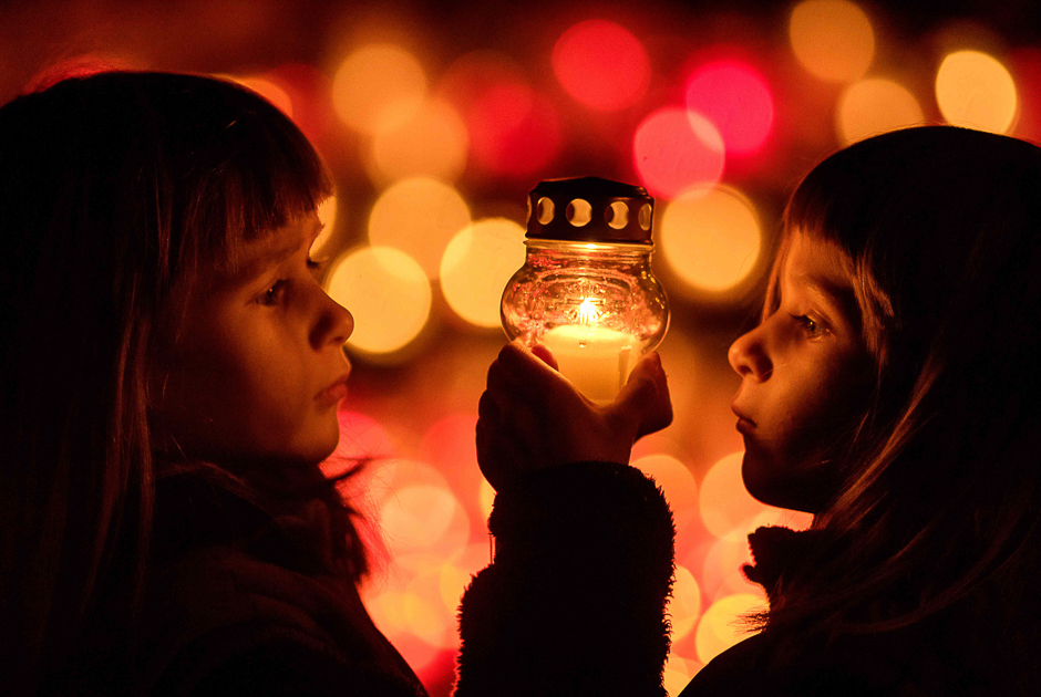 Five-year-old twin sisters Amalia and Lesana play with a candle at the cemetery in the village Ivanka pri Dunaji near Bratislava, Slovakia on the All Saints Day. PHOTO: AFP