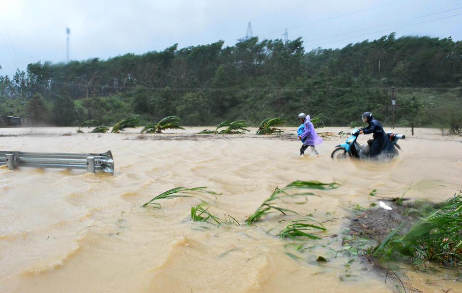 People walk through floodwaters on a highway in the central province of Dak Lak brought by Typhoon Damrey. PHOTO: AFP