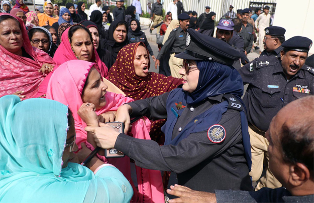 A female police officer tying to stop the protesting lady health workers. PHOTO: ONLINE