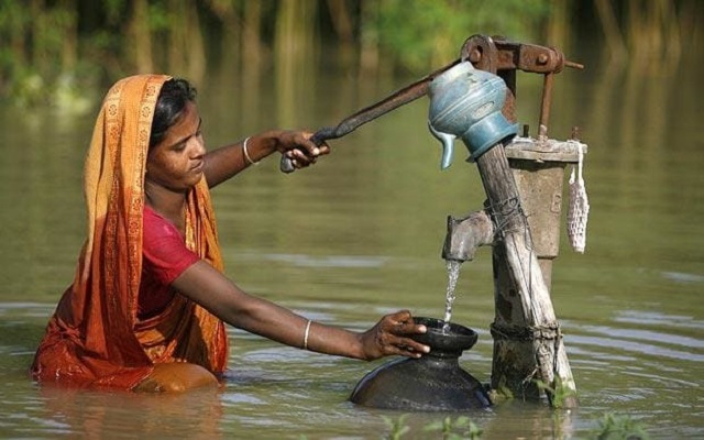 File Photo: A woman collects drinking water in the flooded village of Godadhar, Bangladesh PHOTO: REUTERS