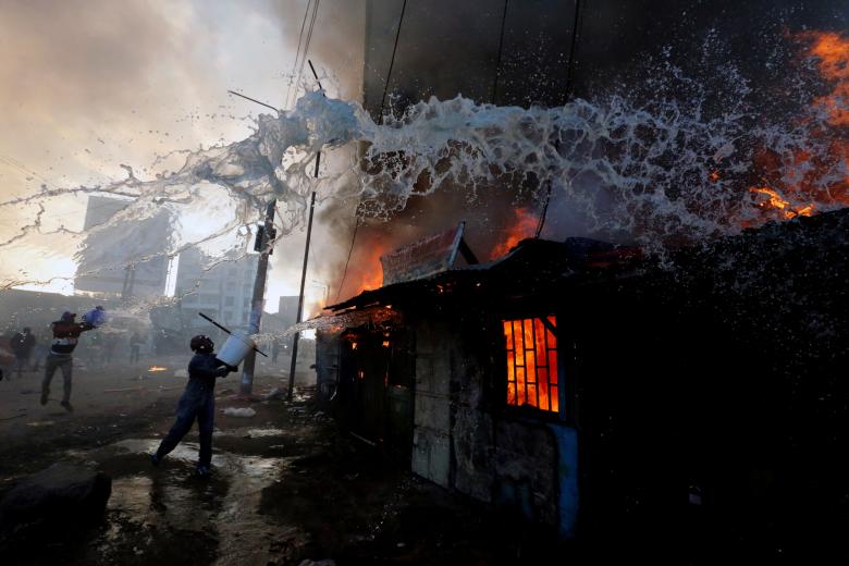 People try to put out a fire at properties set ablaze by rioters in Kawangware slums in Nairobi, Kenya. PHOTO: REUTERS