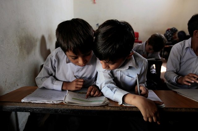 Students share a textbook during an English class at the Mashal Model school in Islamabad, Pakistan, September 26, 2017. PHOTO: REUTERS