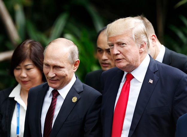 US President Donald Trump (R) and Russia's President Vladimir Putin talk as they make their way to take the 
