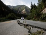 a-crack-runs-through-a-mountain-road-as-a-police-car-approches-after-an-earthquake-outside-jiuzhaigou