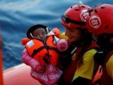 a-crew-member-of-mv-open-arms-carries-a-migrant-baby-before-passing-it-to-crew-members-of-mv-aquarius-during-a-mid-sea-transfer-of-migrants-in-the-central-mediterranean-off-the-coast-of-libya