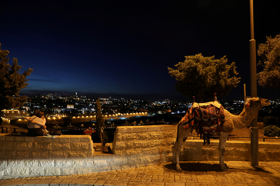 People sit together next to a camel at the look-out point of Mount Olives opposite to the Dome of the Rock and Jerusalem's Old City. PHOTO: REUTERS