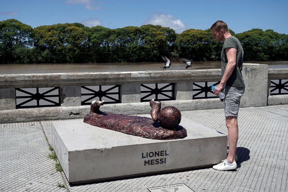 A man looks at the vandalised sculpture of Argentinian football player Lionel Messi, at the 