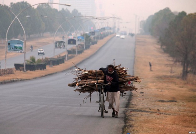 A man pushes a bicycle loaded with tree branches to be used for heating and cooking, on a road in Islamabad. PHOTO: REUTERS