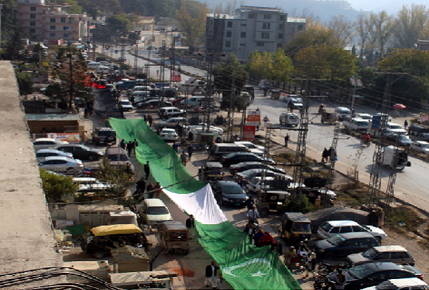 AJK PP workers carrying the long flag to Parade Ground. PHOTO: EXPRESS