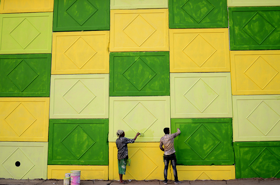 Indian workers paint the wall of a flyover on a road in Jalandhar. PHOTO: AFP