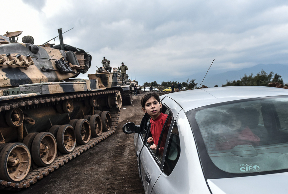 A Turkish girl leans out of a car window to have a look as Turkish army tanks and soldiers gather close to the Syrian border at Hassa, in Hatay province. PHOTO: AFP
