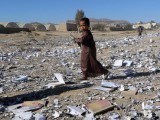 boy-holds-a-book-as-he-walks-on-books-scattered-on-the-ground-after-an-air-strike-hit-a-school-book-storage-building-in-the-northwestern-city-of-saada