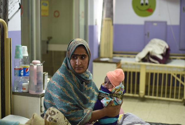 This picture taken on December 15, 2017 shows Sartaj holding her 15-days-old daughter Kinza, who is suffering from diarrhea and a blood infection, in a government hospital in Islamabad. PHOTO: AFP