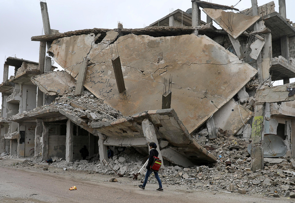 A student walks past rubble of damaged buildings in a rebel-held area in the city of Deraa, Syria. PHOTO: REUTERS