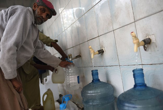 This picture taken on December 14, 2017 shows a man filling bottles at a water filtration plant in Islamabad. PHOTO: AFP