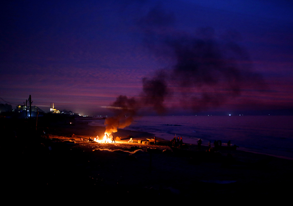 Palestinian fishermen warm themselves by a fire at a beach on a winter day, in the northern Gaza Strip. PHOTO: REUTERS
