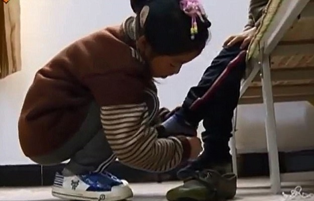 Sibling bond: The girl, from China, helps her brother get dressed before setting out to school. PHOTO COURTESY: WENSHAN TELEVISION STATION