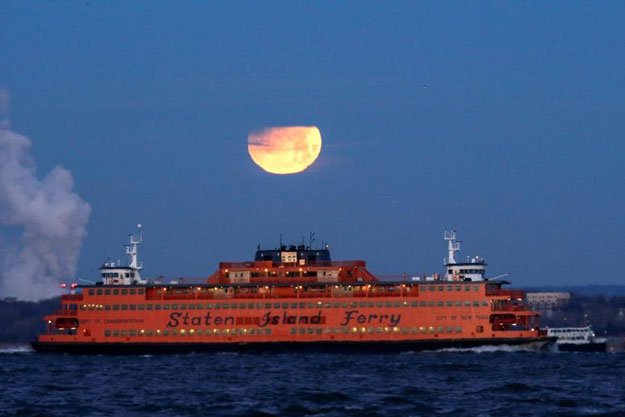 The Super Blue Blood Moon sets behind the Staten Island Ferry, seen from Brooklyn. REUTERS/Eduardo Munoz 