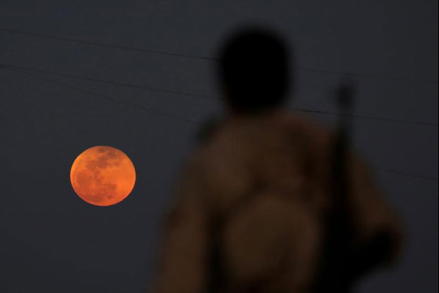 A fighter from Free Syrian Army is seen watching a full moon rises in Daraa, Syria. PHOTO: REUTERS/ Alaa al-Faqir