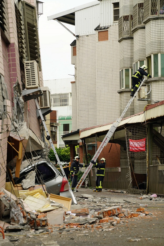 Rescue and emergency workers check for survivors inside a damaged building, the morning after a 6.4 magnitude quake hit the eastern Taiwanese city of Hualien, on February 7, 2018. Rescue workers scrambled to search for survivors in buildings left tilting precariously on their foundations in the Taiwanese city of Hualien on February 7, after an overnight earthquake killed four and injured more than 200. PHOTO:AFP