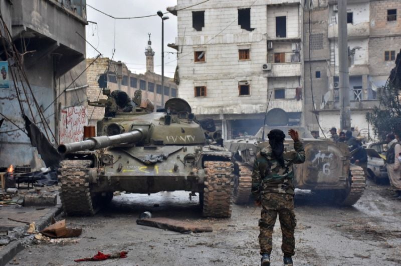 A member of the Syrian pro-government forces gestures to tanks as they patrol the northern embattled city of Aleppo on December 14, 2016. PHOTO: AFP
