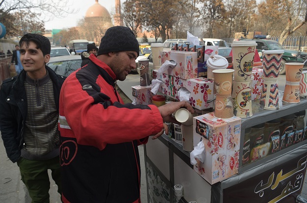 File photo of Najibullah Sharyari with a customer at his coffee cart in Kabul, January 8, 2018. PHOTO: AFP/ File