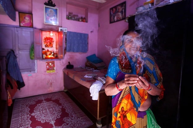 A Hindu woman burns incense sticks as she prays inside her home in the old quarters of Delhi. PHOTO: REUTERS